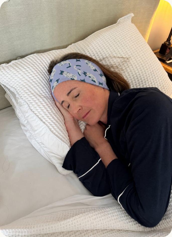 A woman asleep wearing the patterned Clementine sleep band
