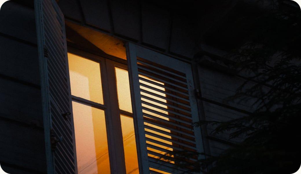 A lit window with shutters at night